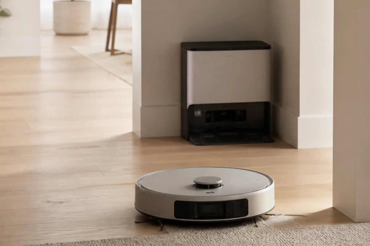 Unbranded robot vacuum moving between wood flooring and a rug in a calm home